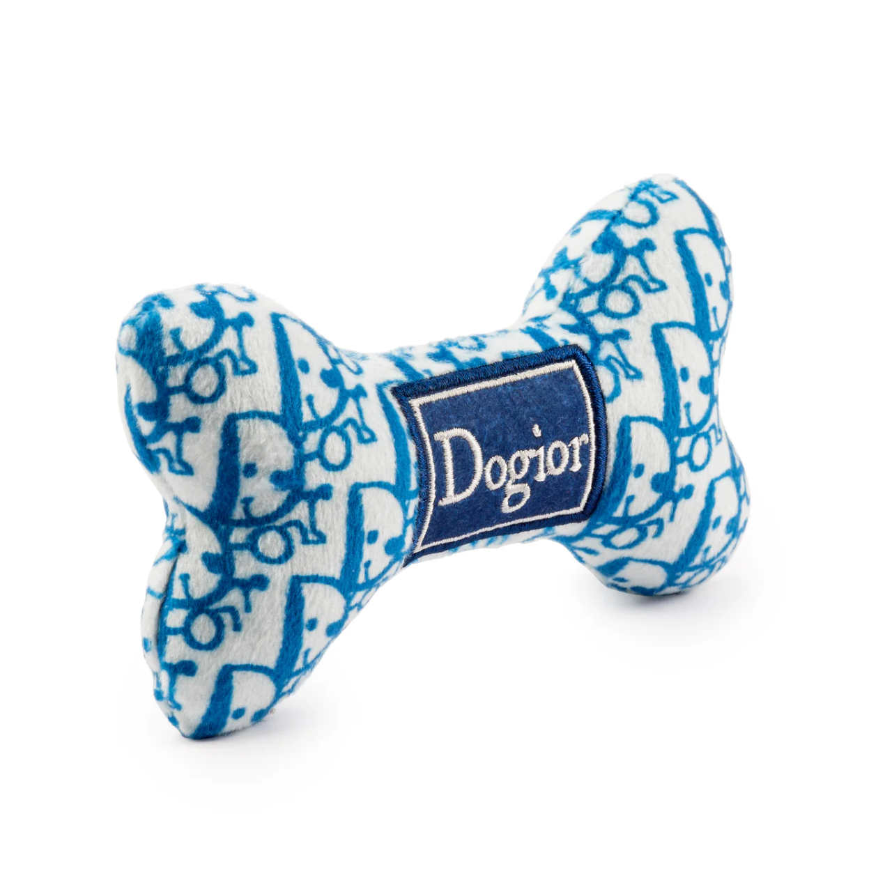 The Dogior Bone by Haute Diggity Dog is a plush dog bone toy featuring a blue and white pattern and a “Dogior” label on the front, photographed against a white background.