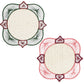 From the Lily & Heliconia Placemat Collection by Mercedes Salazar, this pair of square doilies features rounded corners and showcases thread patterns radiating from circular beige centers—one intricately woven in green and red, the other in pink and red—evoking the vibrant artistry found in traditional Colombian placemats and handwoven raffia designs.