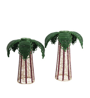 Introducing the Mercedes Salazar Palm Candle Holder & Flower Vase: two handcrafted pieces made from natural raffia fiber, each featuring tall conical bases topped with green, palm-inspired leaves. These unique decorative holders—displayed against a white background—are perfect for showcasing your favorite battery-powered candle or as charming flower vases.