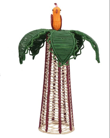 The Hoatzin Palm Candle Holder & Flower Vase by Mercedes Salazar features a woven sculpture of a bird perched atop green leaves, set on a conical base crafted from interlaced natural and maroon fibers—an exquisite piece of handcrafted dining decor.