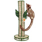 The Mercedes Salazar Monkey Bloom Mico Flower Vase is skillfully crafted with natural raffia fiber for an artisanal touch, featuring a design reminiscent of a tree with a brown monkey figure climbing the trunk and green leaf decorations—an elegant piece inspired by handcrafted dining decor.