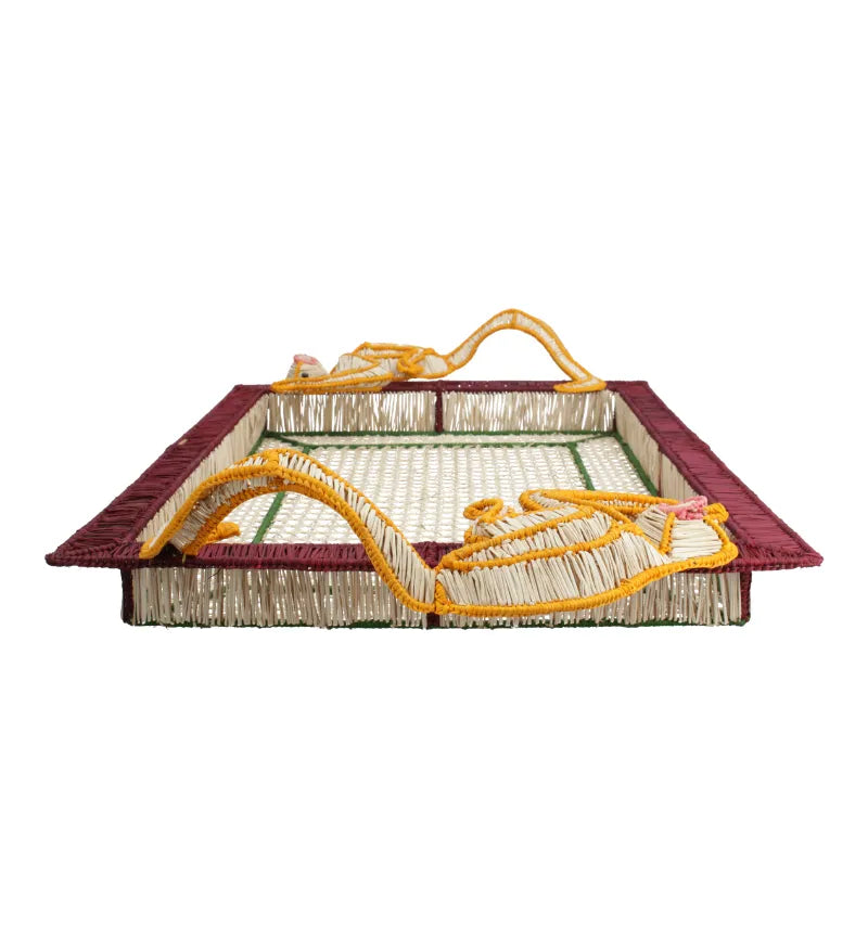 Introducing the Monkey Jungle Party Tray by Mercedes Salazar—a flat woven mat crafted from durable raffia fiber, featuring a maroon border, yellow and pink decorative rope, and a lively green and beige pattern. This artisanal piece adds a unique touch of charm to your dining setting.