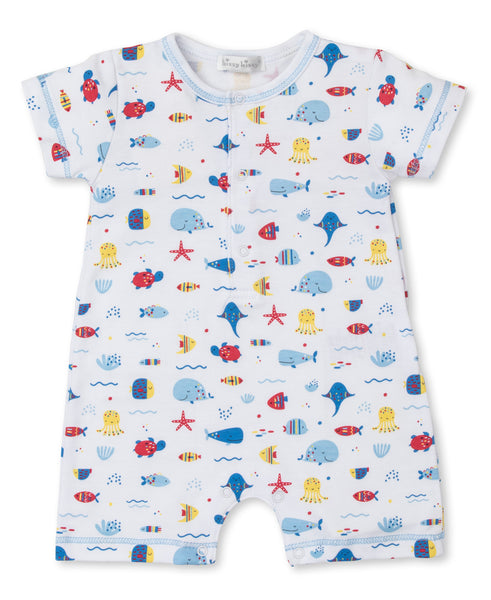 Baby playsuit with a nautical print, featuring whales, sailboats, and waves, displayed on a white background. 
- Kissy Kissy Sea Life Fun Short Playsuit