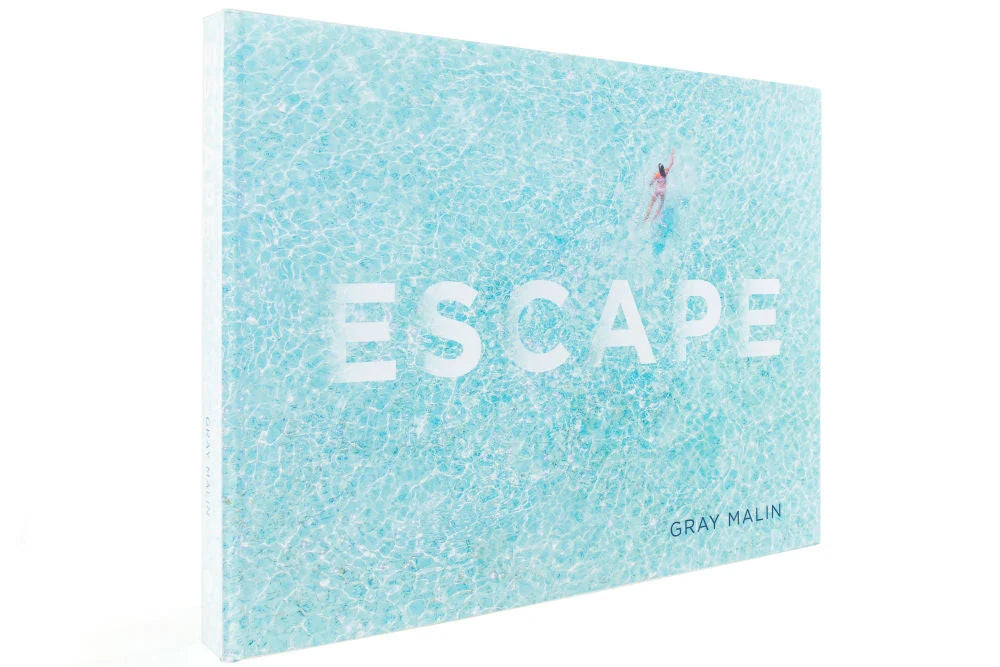 The cover of the Escape book features an aerial view of a person swimming in turquoise water.