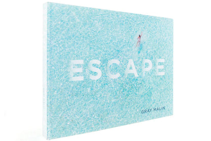 The cover of the Escape book features an aerial view of a person swimming in turquoise water.