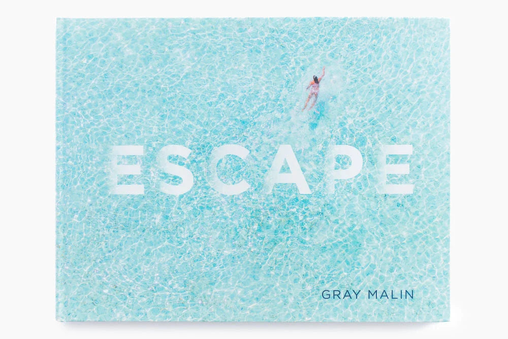 Abrams Escape hardcover photography book featuring an aerial photograph of a person swimming in blue water.