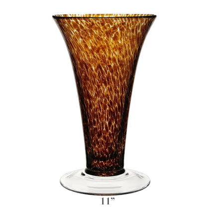 The Vanessa Vase Collection by William Yeoward Crystal features handmade crystal vases with flared rims, mottled amber Mediterranean hues, and clear round bases. Each vase stands 11 inches tall.