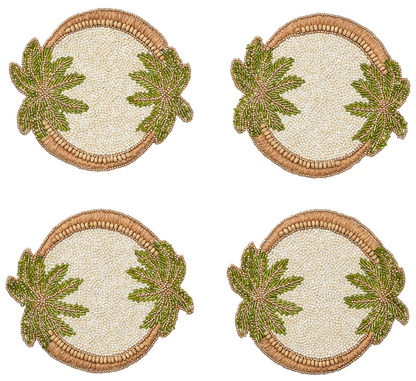 The Oasis Coasters Set by Kim Seybert includes four identical round beaded coasters with tropical designs featuring two green leaves, perfect for cocktail parties. Displayed on a plain white background.