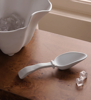 A Beatriz Ball Vida Nube Ice Scoop sits on a wooden surface next to two ice cubes and a white ice container. This stylish melamine scoop is dishwasher safe.