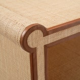 Close-up of the Matthew Coffee Table by Made Goods, showcasing its uniquely shaped corner, woven raffia surface, and dark full-grain leather trim.