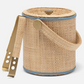 The Gable Natural/White Barware Collection by Blue Pheasant includes a round wicker ice bucket with lid, blue leather trim, handle, and gold tongs—ideal for your raffia bar.
