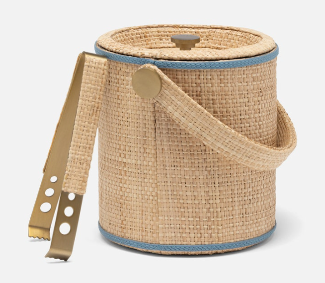 The Gable Natural/White Barware Collection by Blue Pheasant includes a round wicker ice bucket with lid, blue leather trim, handle, and gold tongs—ideal for your raffia bar.
