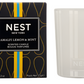 The Nest Amalfi Lemon & Mint Collection candle comes in a white jar with packaging inspired by the Amalfi Coast, featuring a black box adorned with yellow and blue accents.