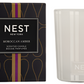 A box labeled "Moroccan Amber Candle Collection" by Nest sits beside a white glass candle holder with the Nest logo, evoking rich patchouli and bergamot notes in its elegant design.