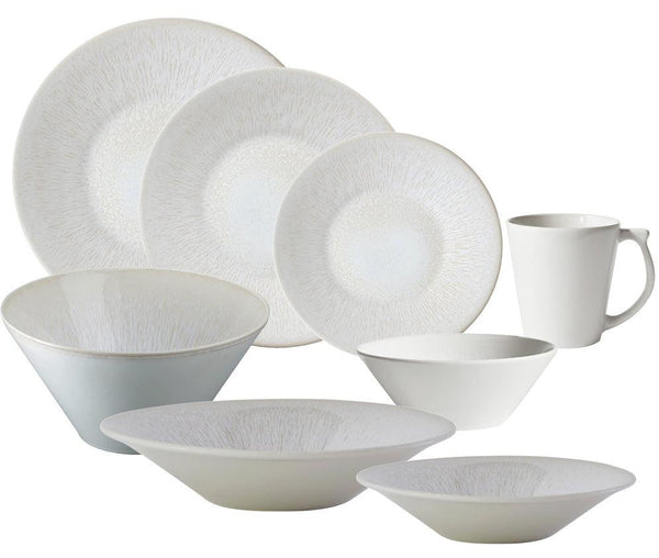 The Jars Vuelta White Pearl Collection by Jars showcases a beautiful white ceramic dinnerware set, which includes plates, bowls, a mug, and a stylish dessert plate. Each piece features subtle textured designs and a perle glaze, all arranged neatly in the display. This collection is not only elegant but also dishwasher safe for added convenience.