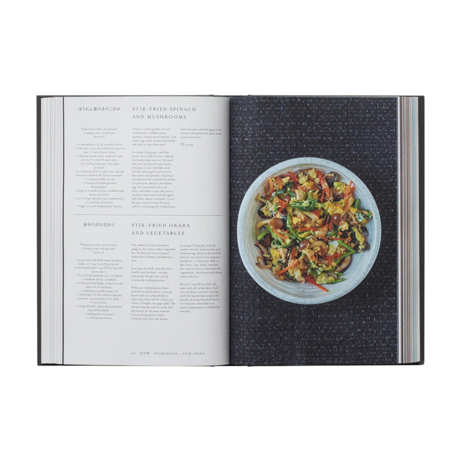 Japan: The Cookbook by Phaidon is open to a recipe on the left and a bowl of stir-fried vegetables on the right, all set against a dark textured background.