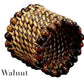 The Calaisio Woven Napkin Ring is handmade by artisans from walnut-colored water-vines and features dark and light wooden beads around the edge. "Walnut" appears in the lower left corner.