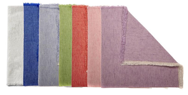 Seven napkins, crafted from linen/cotton blends in white, blue, gray, green, red, pink, and purple by Deborah Rhodes, are neatly arranged like a vibrant collection. The no-iron purple Deborah Rhodes Washed Fringe Napkin is partially folded for an elegant accent.