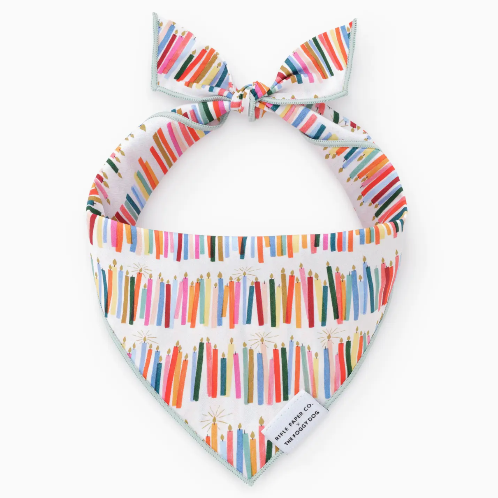 The Birthday Candles Dog Bandana by Foggy Dog is a white triangle bandana with colorful birthday candle patterns, a top knot, and a sewn "FOGGY DOG" label—perfect for celebrating your pup’s special day.