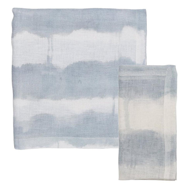 Two pieces of the Kim Seybert Watercolor Stripe Linen Collection in white and blue, one folded and one flat against a white background; ideal for adding a summer splash to your dining table.