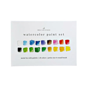 The Emily Lex Studio Watercolor Paint Set is a white box labeled with its name, featuring 18 color swatches in two rows. The packaging also lists included items—a metal tin, palette, and round brush—making it an ideal travel watercolor kit for artists on the go.