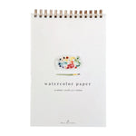 Emily Lex Studio Spiral Watercolor Paper Pad featuring an illustrated paint palette and brush on the cover, labeled “watercolor paper 12 sheets | 110 lb | 5 x 7 inches.”.