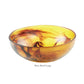 A large, round glass bowl with amber and brown swirls—part of the Tortoise Resin Serveware Collection by Nashi Home—adds elegant, shatter-resistant style to your home decor.