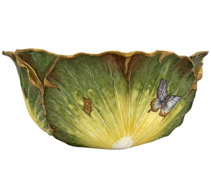 The Anna Weatherley Cabbage Bowl is a Hungarian porcelain piece shaped like a green cabbage leaf, featuring hand-painted gold accents and a butterfly motif in the brand’s signature style.