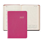 A closed 2027 Weekly Notebook in pink from Graphic Image is placed in front of an open planner displaying a weekly layout for July; both showcase lined pages and calendar sections—making them the perfect elegant appointment book or stylish leather notebook to keep you organized year-round.