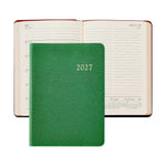 A closed 2027 Weekly Notebook by Graphic Image in green, styled like a sleek leather notebook, is displayed in front of an open weekly appointment book showing dates from July 12 to July 18.