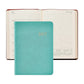 A Graphic Image 2027 Weekly Notebook in teal is placed on top of an open weekly appointment book displaying the week of July 12–18, with calendar overviews for July, August, and September 2027 visible.