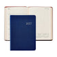 A 2027 Weekly Notebook by Graphic Image in blue rests closed atop an open weekly planner displaying the dates July 12 to 18, featuring a small yearly calendar at the bottom of the page and evoking the classic style and functionality of an appointment book.