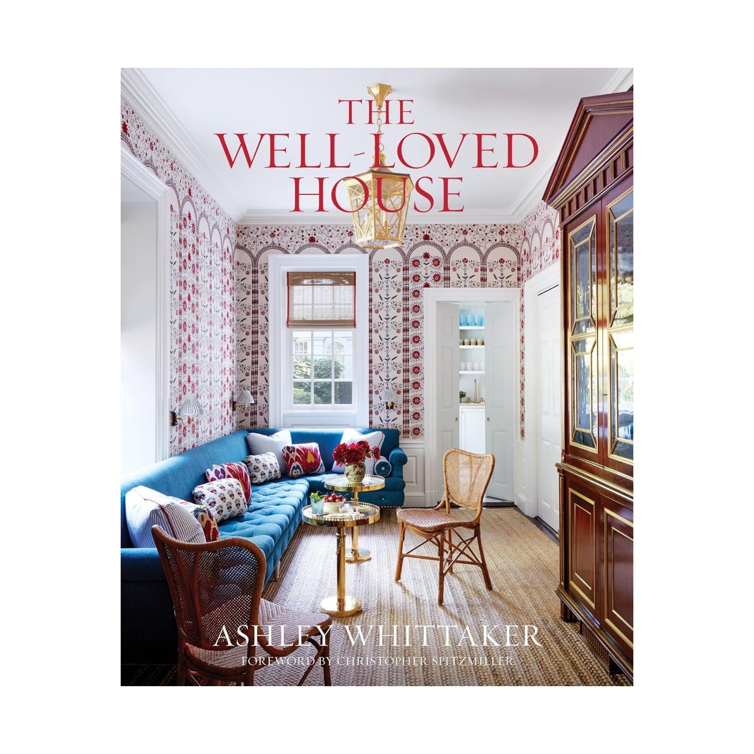 Book cover of The Well-Loved House from Penguin Random House, showcasing a vibrant, traditional living room with patterned wallpaper and a blue sofa—a perfect representation of the neo-traditionalist interior design style that defines Ashley Whittaker’s work.