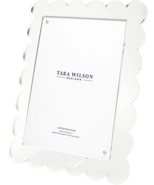 The Clear Scallop Frame, 8 x 10 by Tara Wilson Designs is an upright acrylic frame with scalloped edges, a lucite finish, and removable kickstand—an elegant wedding gift that comes with a branded insert.