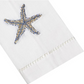 Haute Home’s Starfish Coaster & Bath Collection features a white Italian linen cloth napkin, adorned with a blue and gold beaded starfish design and displayed diagonally on a white background—a standout piece for refined linen home décor.
