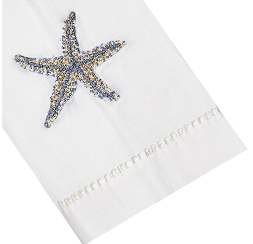 Haute Home’s Starfish Coaster & Bath Collection features a white Italian linen cloth napkin, adorned with a blue and gold beaded starfish design and displayed diagonally on a white background—a standout piece for refined linen home décor.