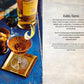 A cocktail garnished with a lemon twist rests on a gold tray beside a glass of nuts, accompanied by a bottle of Glenmorangie whisky and an extra glass, all arranged on a blue surface—ideal inspiration for anyone browsing Whiskey Cocktails from Simon & Schuster or searching for their next favorite whiskey recipe.