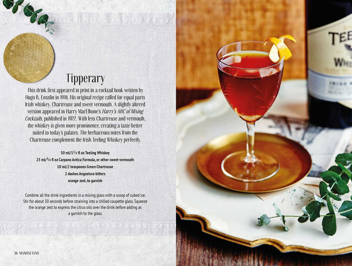 A red cocktail garnished with an orange twist sits on a gold tray next to a Teeling whiskey bottle and a Simon & Schuster Whiskey Cocktails recipe book open to a cocktail recipe.