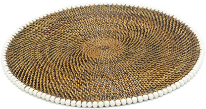 The Calaisio Round Placemat features a handcrafted spiral design in brown tones, made from natural vines and accented with evenly spaced small white beads along the edge.