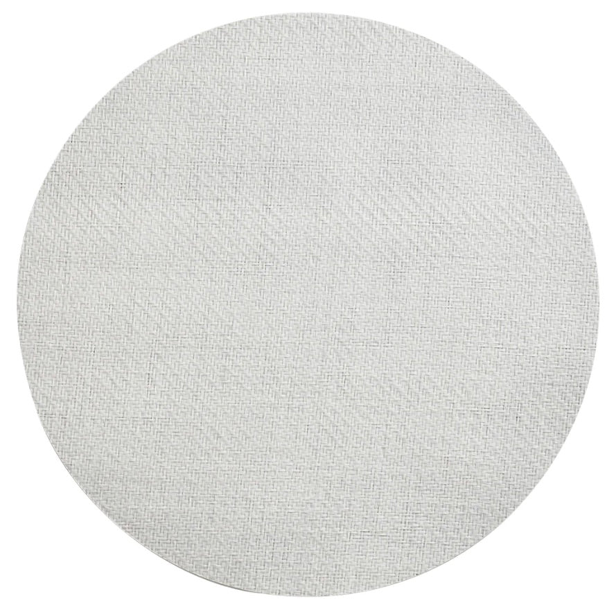 The Kim Seybert Saigon Placemat is a round, light gray swatch with a subtle woven texture inspired by Vietnamese plaiting, shown on a plain white background.