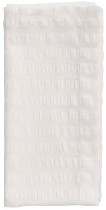 The Seersucker Napkin Set by Kim Seybert features folded white napkins with a textured ribbed pattern and delicate hand-crocheted borders.