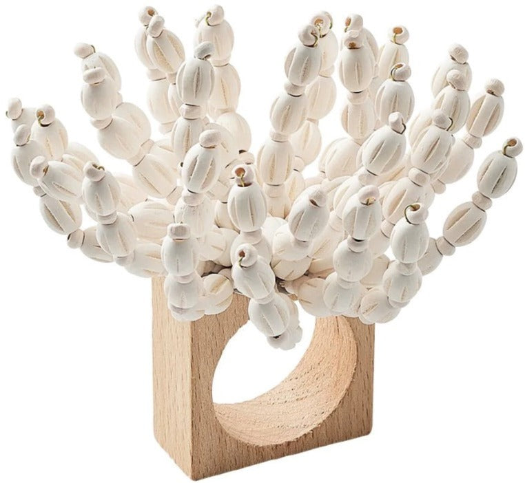 The Reed Napkin Ring by Kim Seybert features wooden beads and white strands, artfully arranged for a coastal-inspired decor accent.