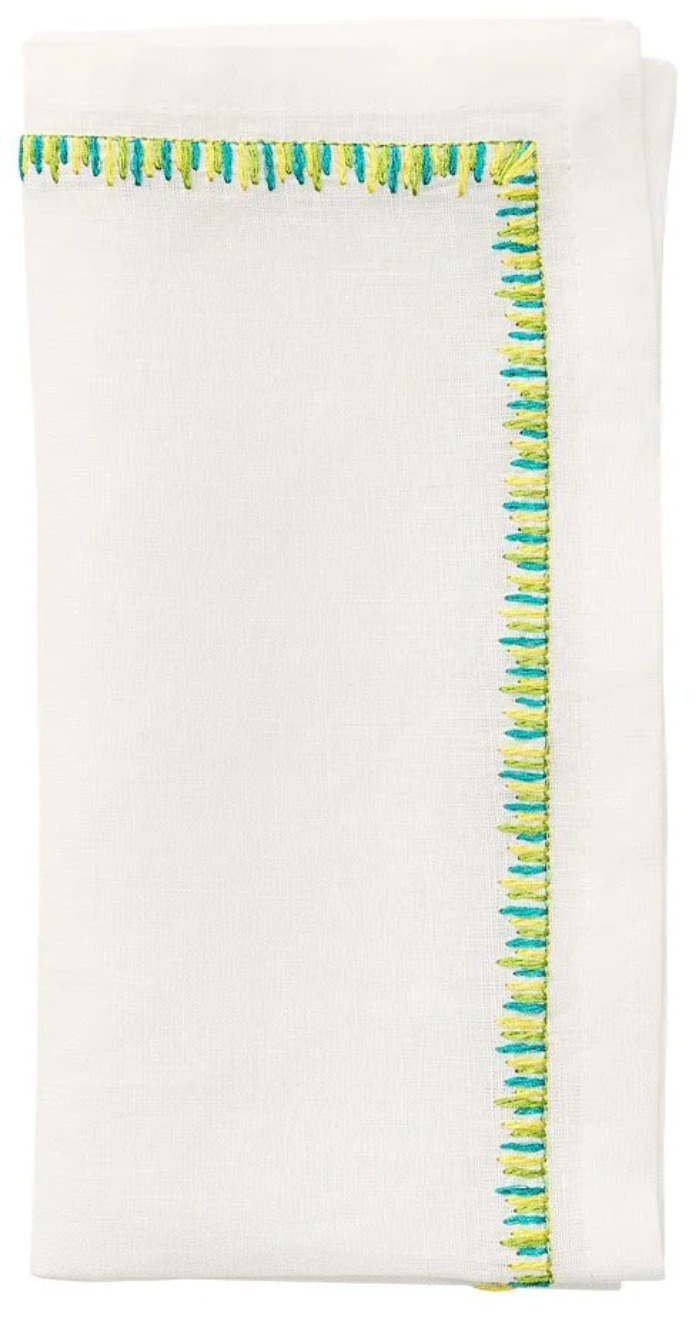 The Kim Seybert Filament Napkin Set includes crisp white linen napkins, neatly folded and accented with delicate blue and green embroidered stitching along one edge.