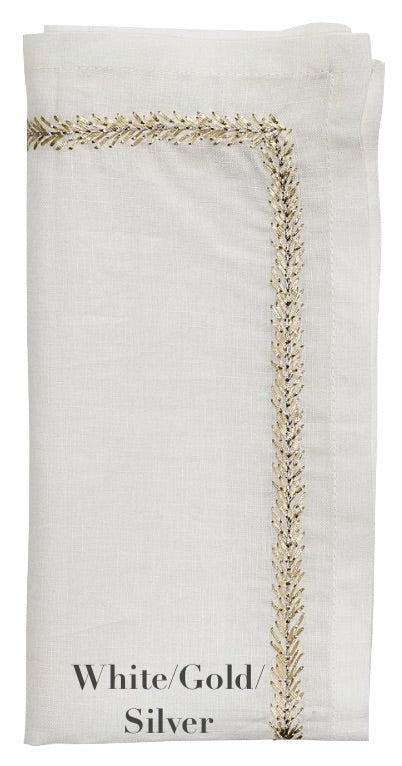 A folded white linen napkin from the Kim Seybert Jardin Napkin Set features gold and silver embroidery along the border, labeled "White/Gold/Silver" at the bottom.