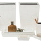 The Callas Bath Collection by Pigeon & Poodle features white mosaic-finished accessories—tissue box, soap dispensers, trays, containers, waste bin, and soap dish—elegantly arranged on a white surface.