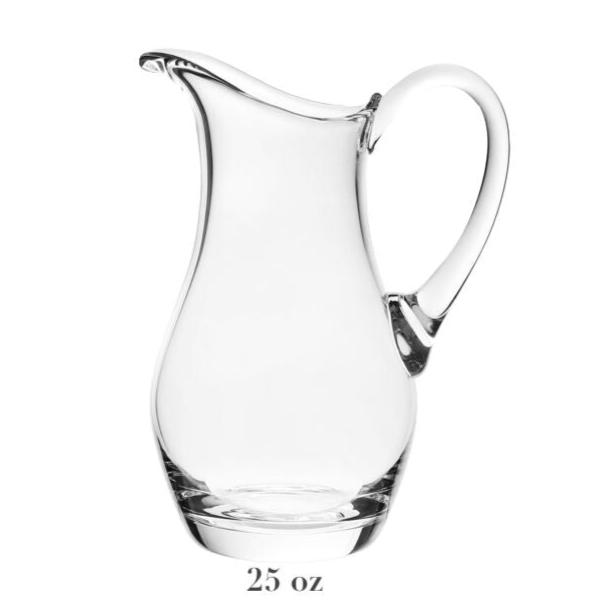 The Whitney Pitcher Collection by William Yeoward Crystal features a clear handmade jug with a curved handle and 25 oz capacity, shown empty against a white background—an elegant wedding gift or stylish way to serve drinks.