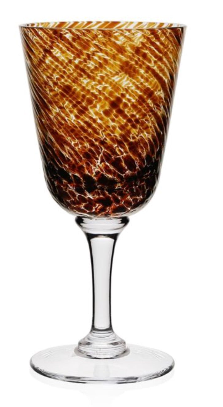 The Vanessa Tortoise Collection wine glass by William Yeoward Crystal features a clear stem and a bowl with a brown, orange, and yellow marbled pattern that creates an elegant optical illusion.