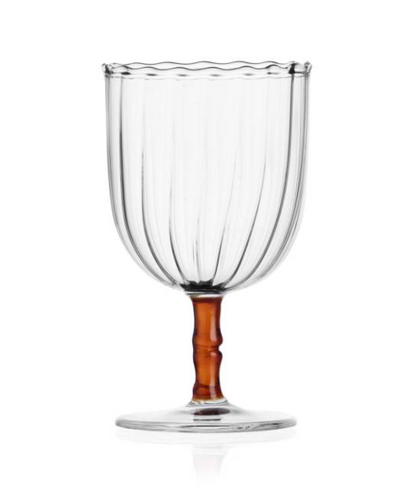 The Rivoli Drinkware and Tealight Collection by Ichendorf Milano features a clear glass goblet with vertical grooves, a wavy rim, brown stem, and round base—a stunning example of hand-crafted glassware.