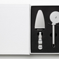 The Essentials Pizza Tools by PrintWorks includes a stainless steel pizza cutter and pie server in a black foam insert inside an open white box, making it a great addition to any pizza kit.