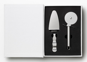 The Essentials Pizza Tools by PrintWorks includes a stainless steel pizza cutter and pie server in a black foam insert inside an open white box, making it a great addition to any pizza kit.